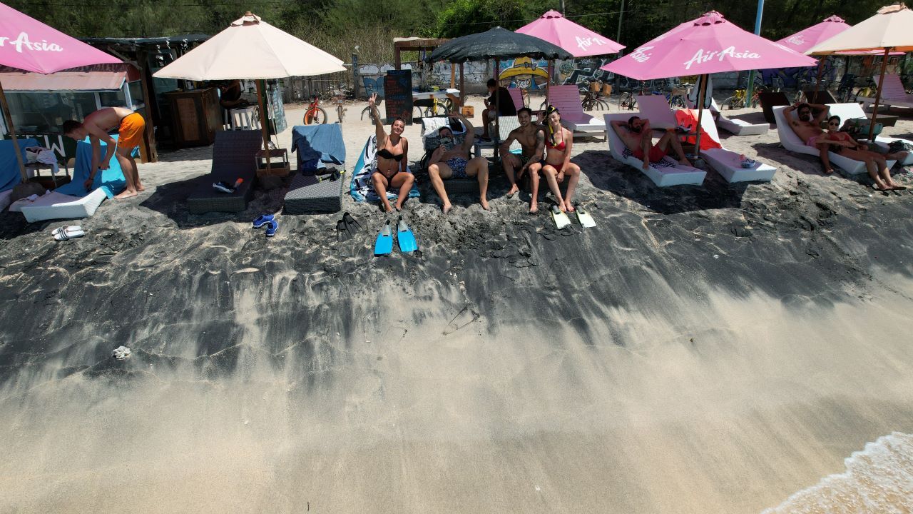 ruta por indonesia sombrillas y hamacas en una playa y chica saludando a la cámara